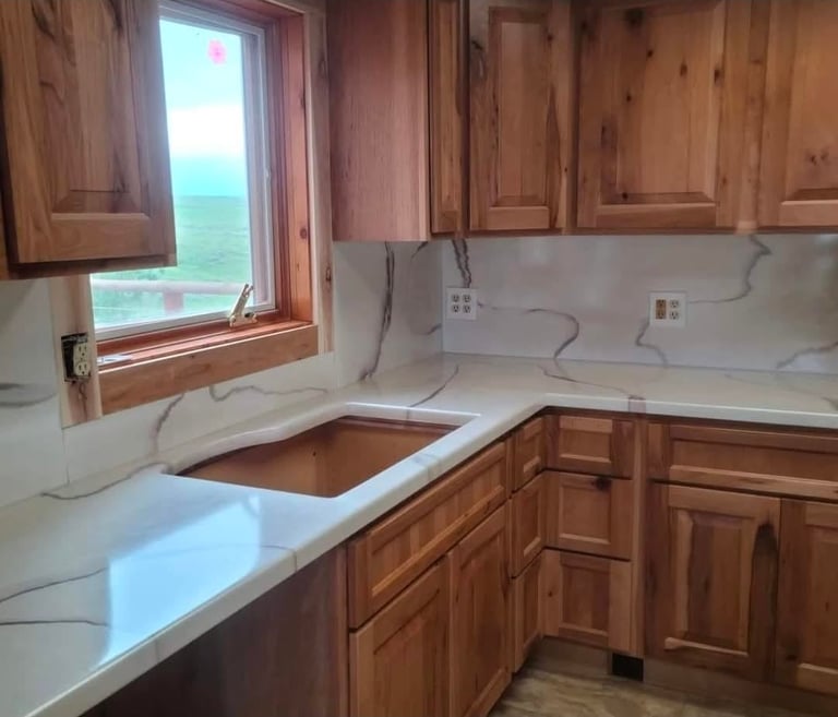 Kitchen with wood cabinets, white marble countertops, and a window overlooking water