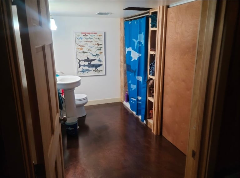 Interior hallway with wooden doors, shark poster on wall, and glimpse of bathroom with fixtures visible