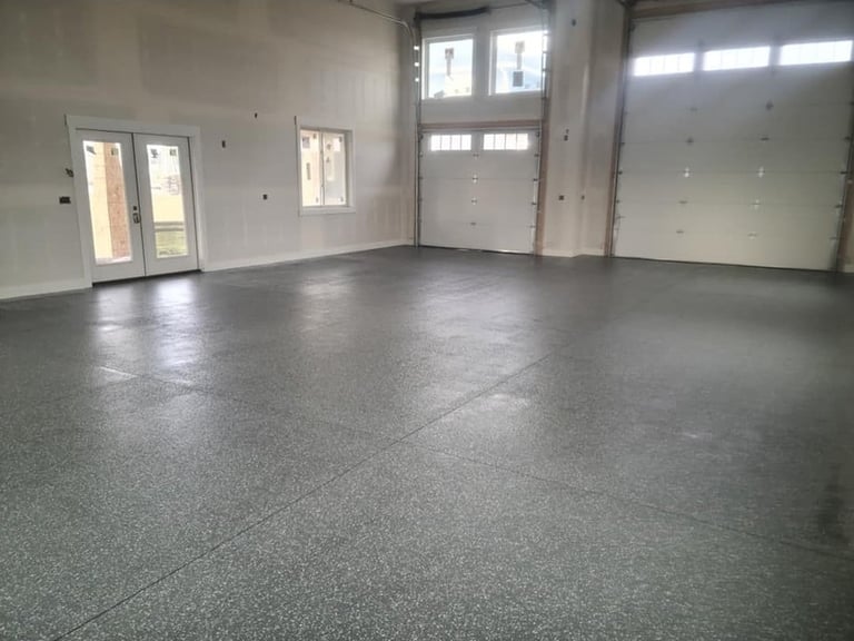 Empty garage interior with polished concrete floor, white drywall walls, and multiple doors including two overhead garage doors with windows