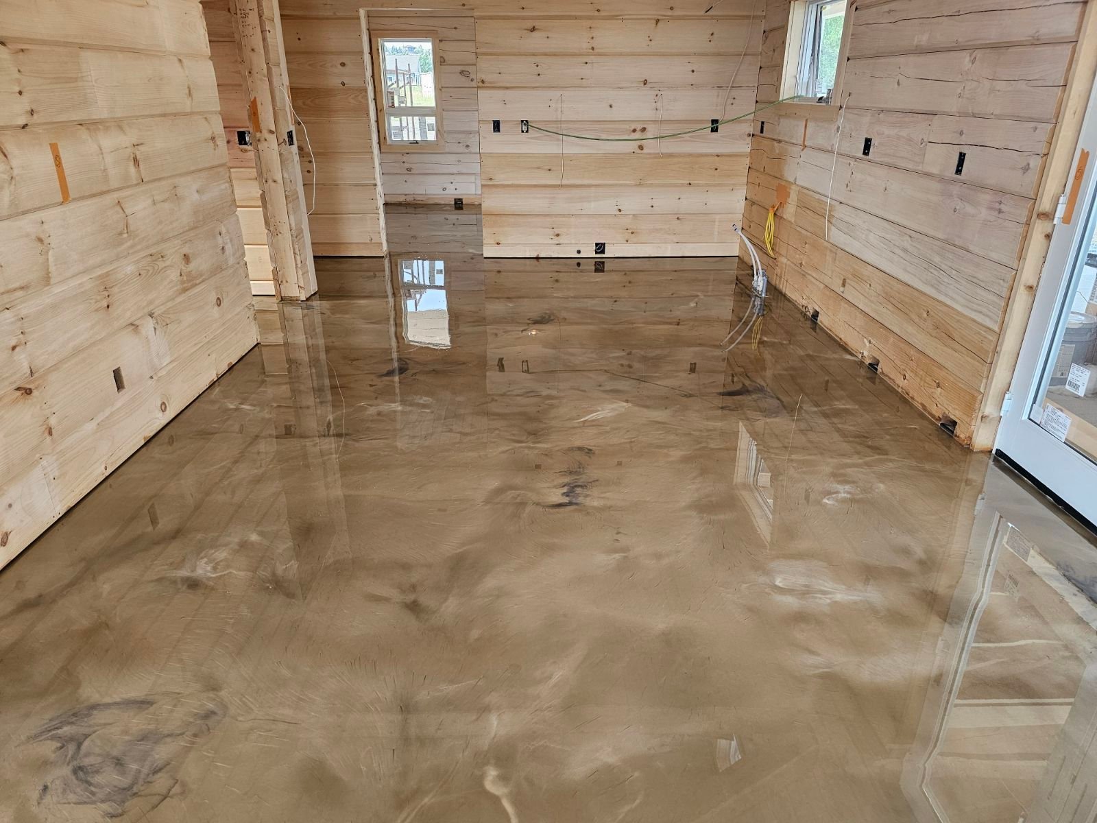Empty interior of wooden cabin under construction with concrete floor and light coming through windows
