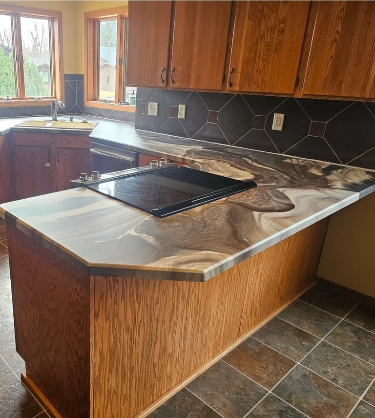 Kitchen with wooden cabinetry, center island with stainless steel cooktop, black geometric backsplash tile, and windows overlooking garden