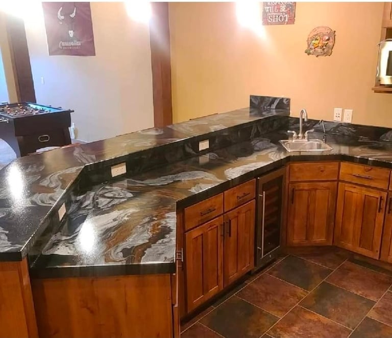 Modern kitchen with L-shaped black and gold granite countertops, wood cabinetry, and tile flooring with peach walls