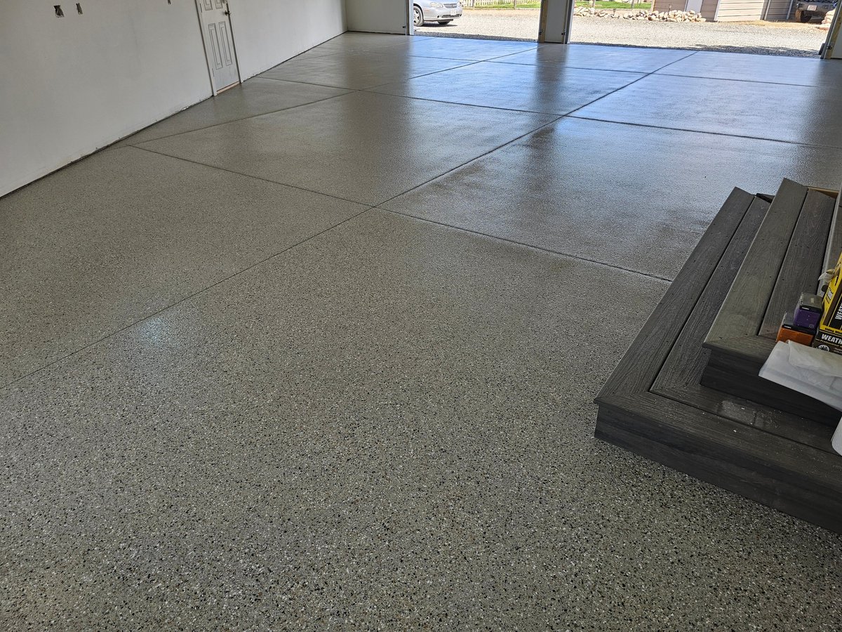 Garage interior with concrete floor, epoxy coating, and metal trim strips installed along the floor seams