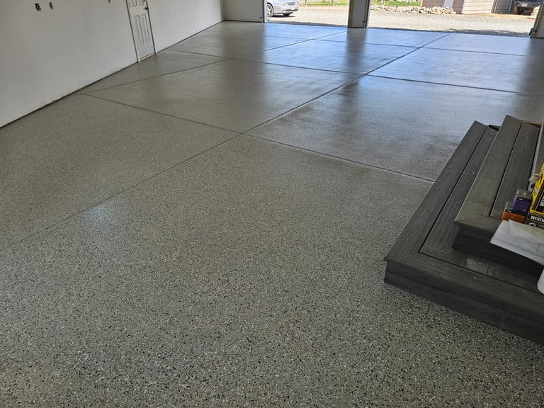 Garage interior with concrete floor, epoxy coating, and metal trim strips installed along the floor seams