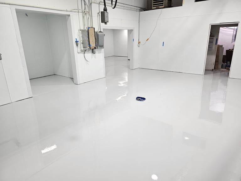 Empty white cleanroom or lab space with polished epoxy floor, equipment mounted on walls, and multiple doorways