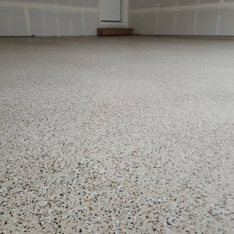 Polished concrete garage floor with speckled aggregate finish and white walls with garage doors in background