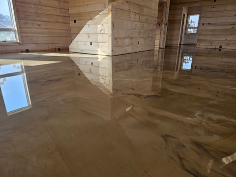 Flooded wooden interior with wet concrete floor reflecting light through windows and doorways
