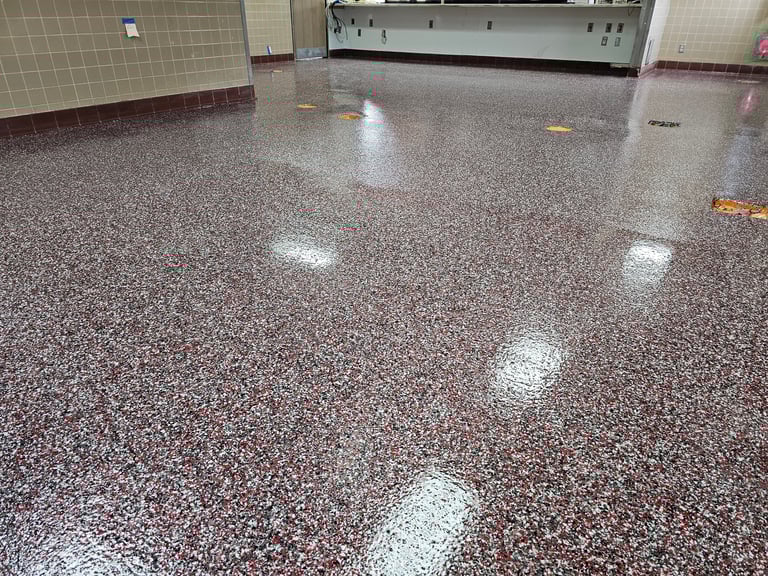 Polished concrete floor with white speckles in a commercial kitchen or food service area with tiled walls