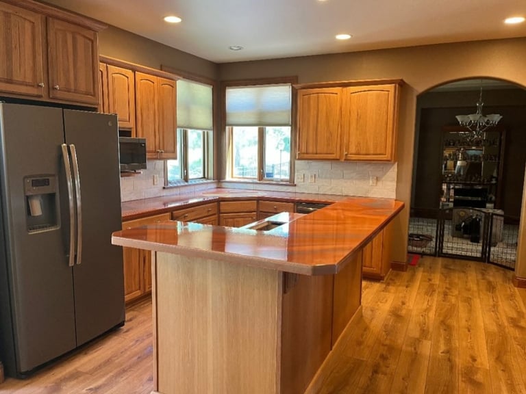 Modern kitchen with wood cabinetry, stainless steel appliances, island counter, and hardwood flooring