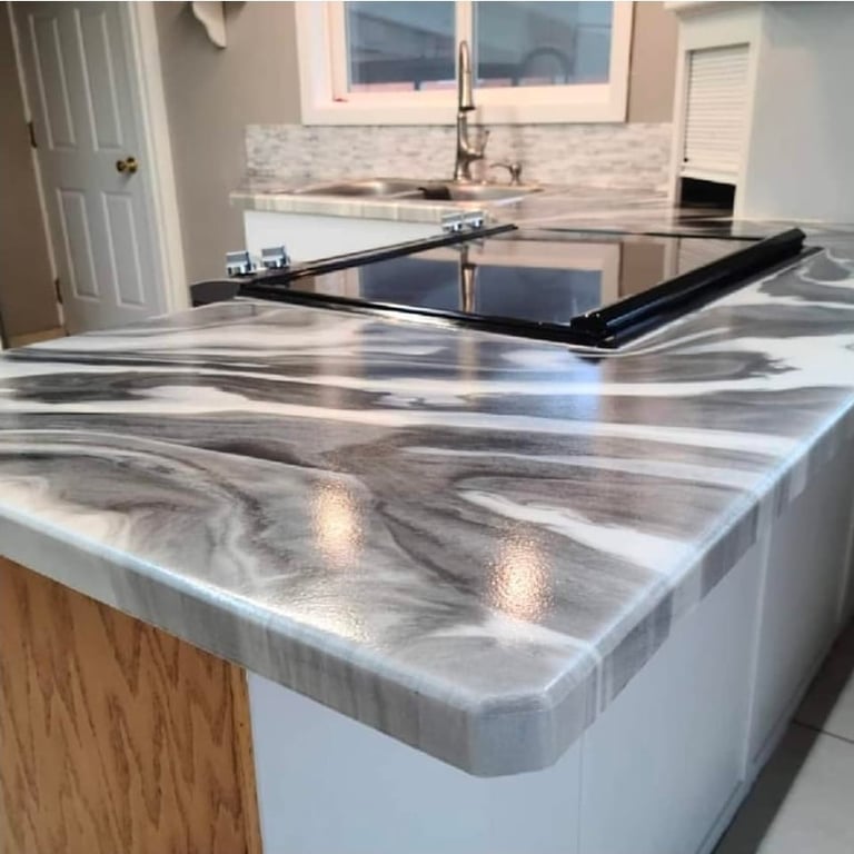 Modern kitchen with gray marble-patterned countertops, stainless steel sink, and black range hood in an island layout