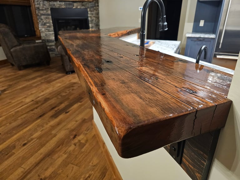 Long wooden countertop with dark stain extending into an open kitchen and living area with hardwood flooring