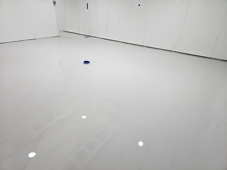 Empty white room with white walls and floor, small blue and white objects scattered on the ground