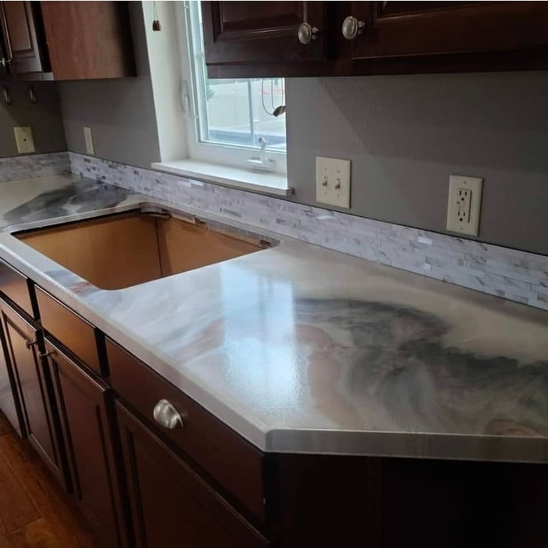 Modern kitchen counter with white marble backsplash, dark wood cabinets, and an undermount sink opening