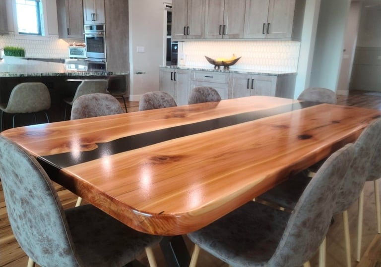 Modern dining room with a live-edge wooden table, gray upholstered chairs, and contemporary kitchen with white cabinetry in the background