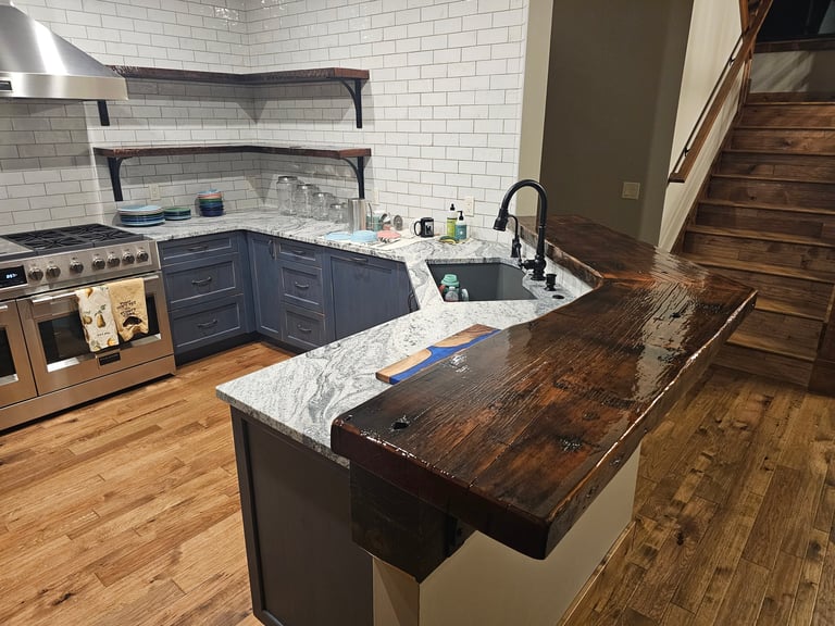 Modern kitchen with dark blue cabinetry, marble countertops, wooden island, stainless steel appliances, and white subway tile backsplash