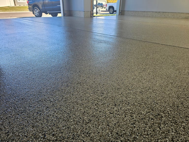 Polished concrete garage floor with blue and gray epoxy coating, vehicles visible in background