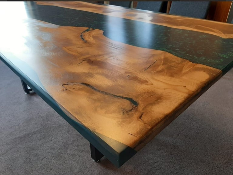 Large wooden dining table with live edge wood top and dark metal base on concrete floor