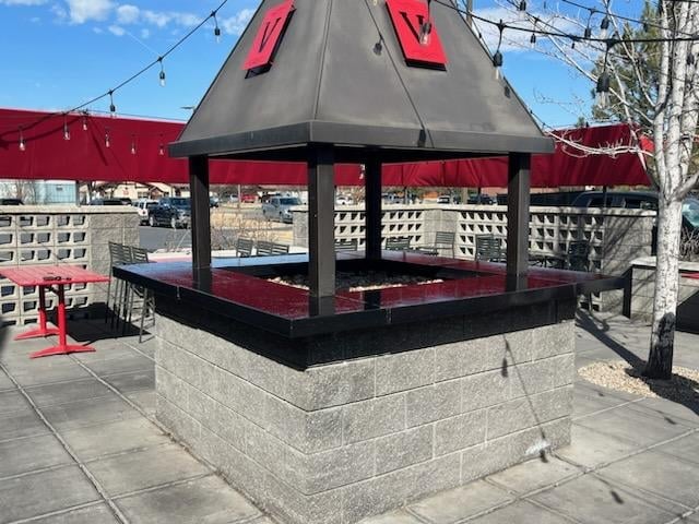 Outdoor kiosk with red and black canopy roof on concrete foundation in urban plaza