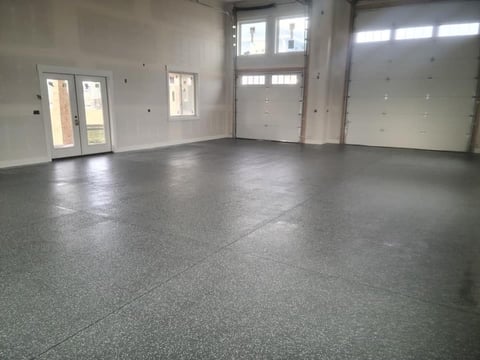 Empty garage interior with polished concrete floor, white walls, and multiple doors with windows