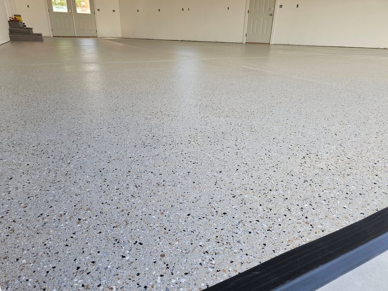Empty garage interior with polished concrete floor speckled with white and black aggregate and white walls